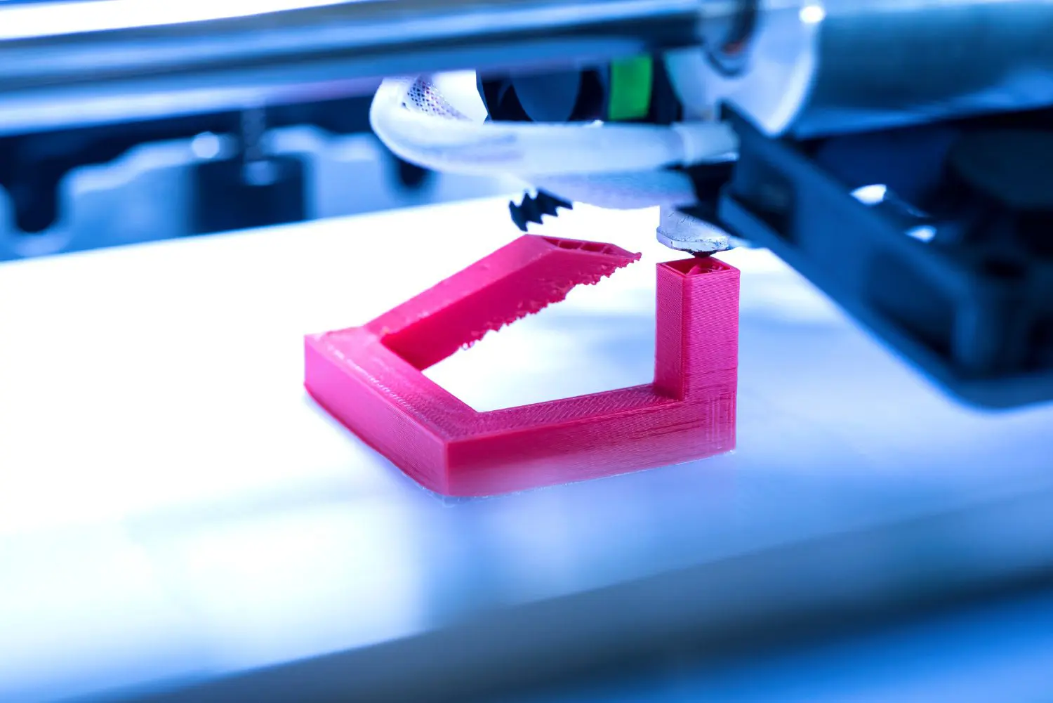 3D printer creating a red plastic object.