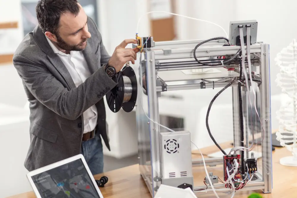 Man adjusting a 3D printer in office.