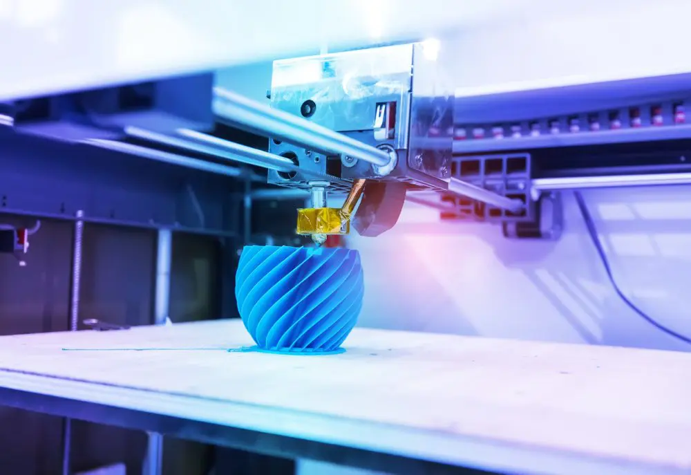 3D printer creating blue geometric object.